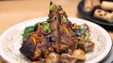 A closeup of a Porkbelly dish with greens and potatoes.